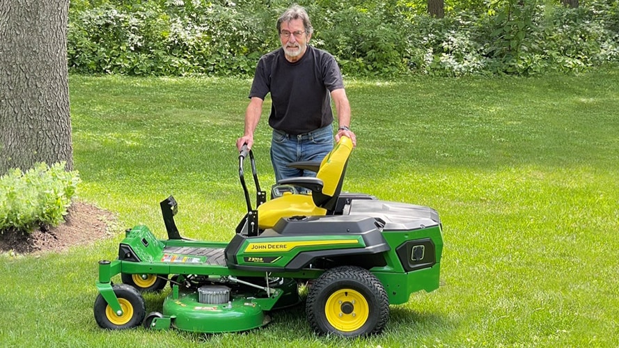 Ralph Nudo standing with his John Deere Z370R electric mower 