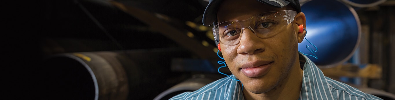 African-American man wearing protective eye wear and ear protection looks on