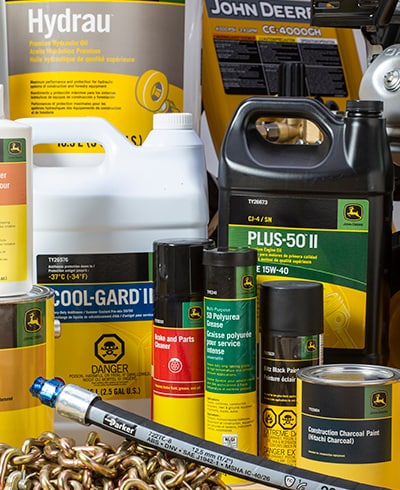 Group of John Deere coolants, paints, cleaners, chemicals, greases, oils, chains, and hydraulic hoses sitting on top of workshop bench