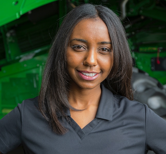 African-American woman standing in next to a harvester looking toward the camera