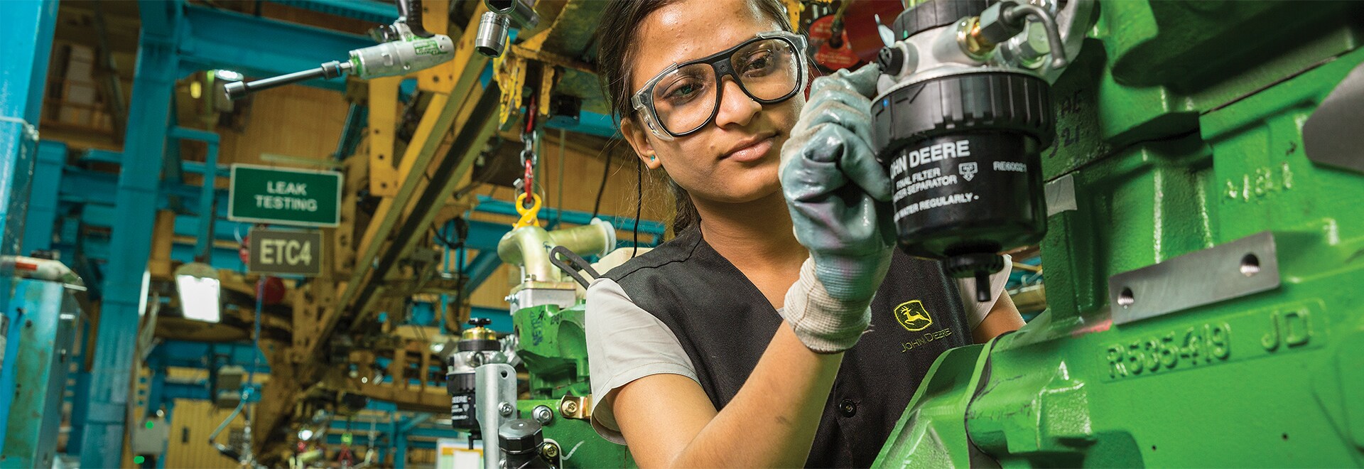 a woman in a workshop working on Deere machinery