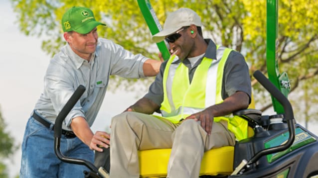 a Deere Dealer talking to a man on a mower