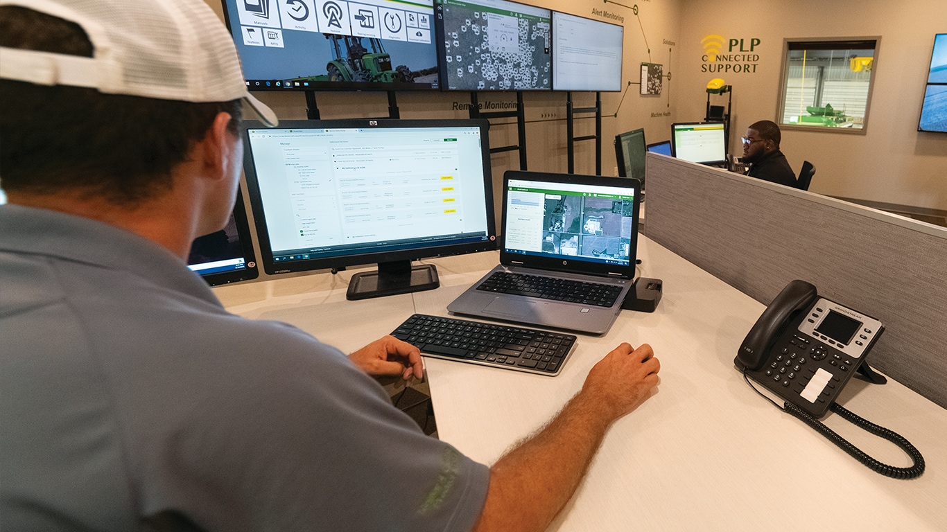 man sitting in front of computer monitors