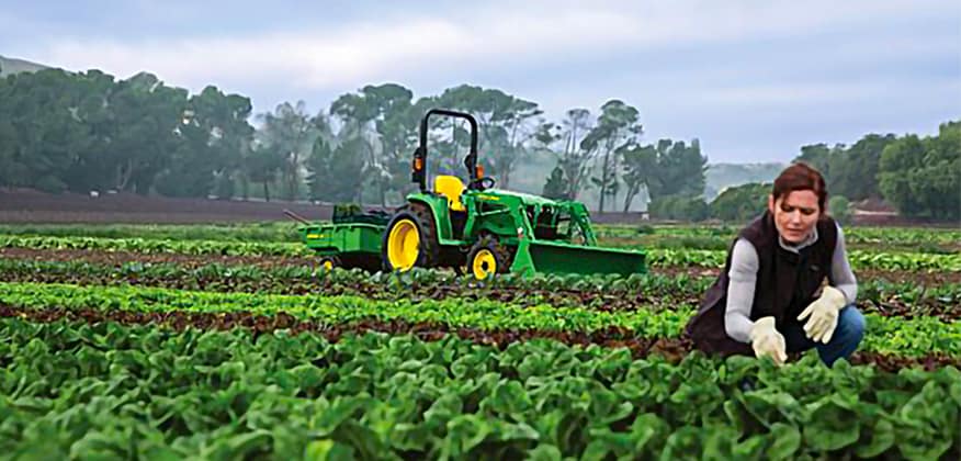 A woman in a field with a tractor in the background