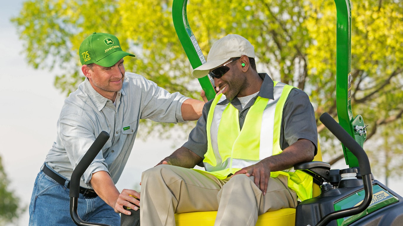 a Deere Dealer talking to a man on a mower