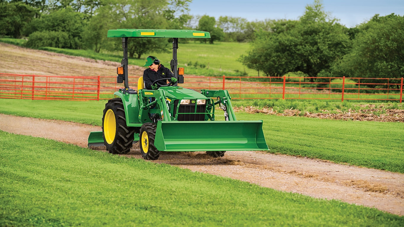 a John Deere tractor with an attachment operating on a dirt path