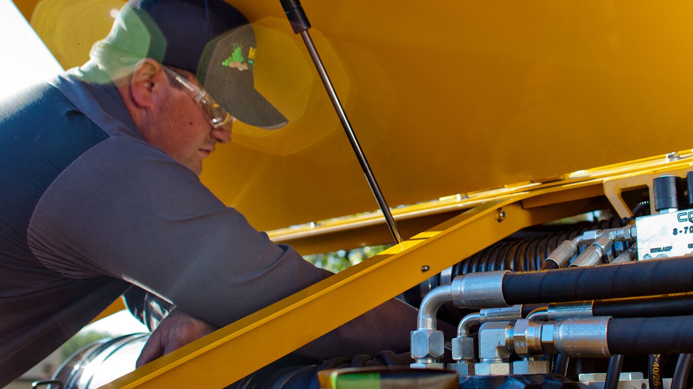 man working under a yellow hood on an engine