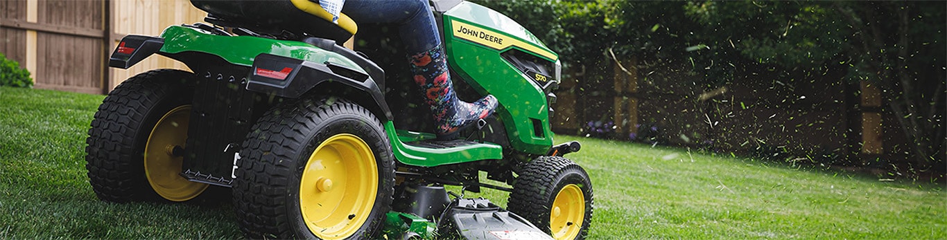 Woman mows lawn on a John Deere riding mower