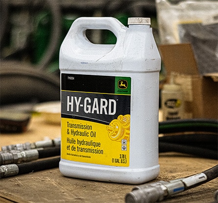 A container of Hy-Gard Transmission & Hydraulic Oil on a work bench surrounded by equipment parts.