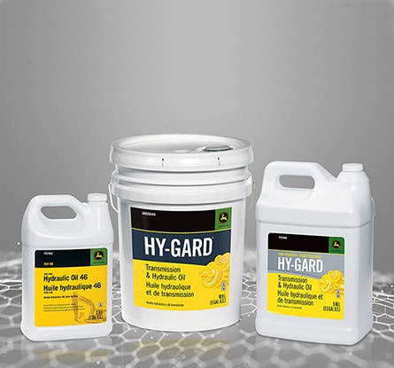 Three white containers of Deere Hy-Gard hydraulic oil on a gray digitized surface.