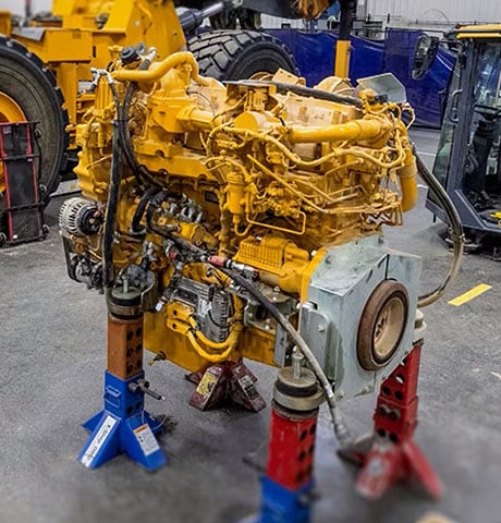 A yellow John Deere engine waiting to enter the remanufacturing process.
