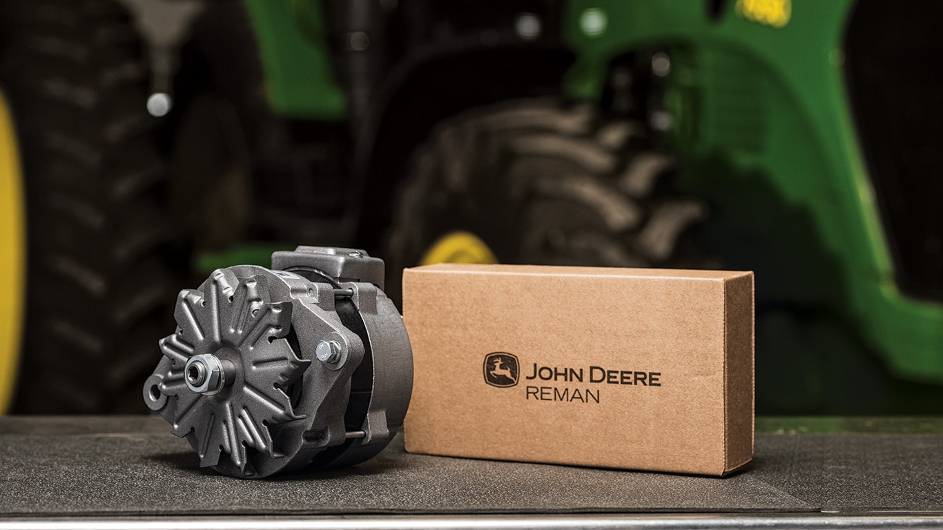 A John&nbsp;Deere Reman tractor alternator and box sitting on a worktable.