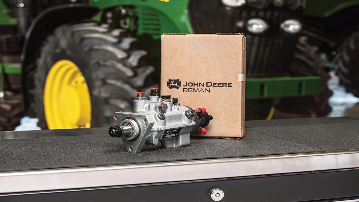 A fully remanufactured John Deere Reman tractor fuel pump and box sitting on a worktable.