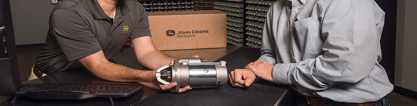 A John&nbsp;Deere dealer discussing the benefits of a John&nbsp;Deere Reman starter with a customer.