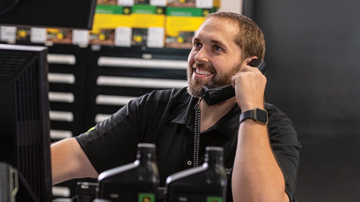 A John Deere dealer talking on the phone to a customer.