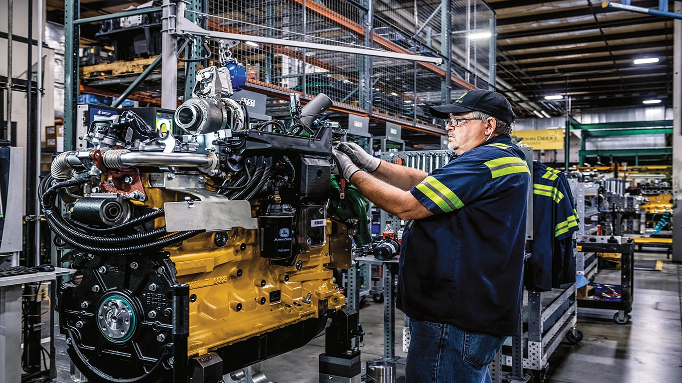 A John Deere Reman technician replacing parts on an engine.