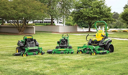 Three commercial mowing lawn equipment machines in a yard