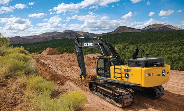 470G LC Excavator digs a trench in front of a mountain range