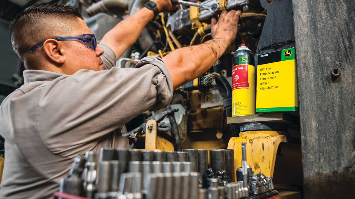 man fixing engine with John Deere parts