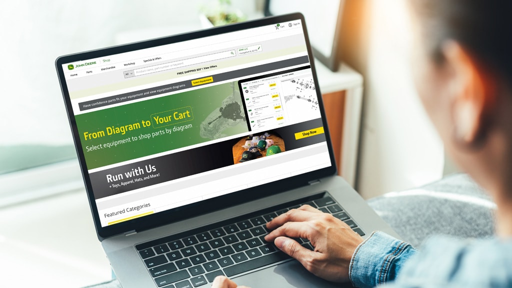 Customer looking at laptop computer screen, reviewing the Shop.Deere.com webpage. 