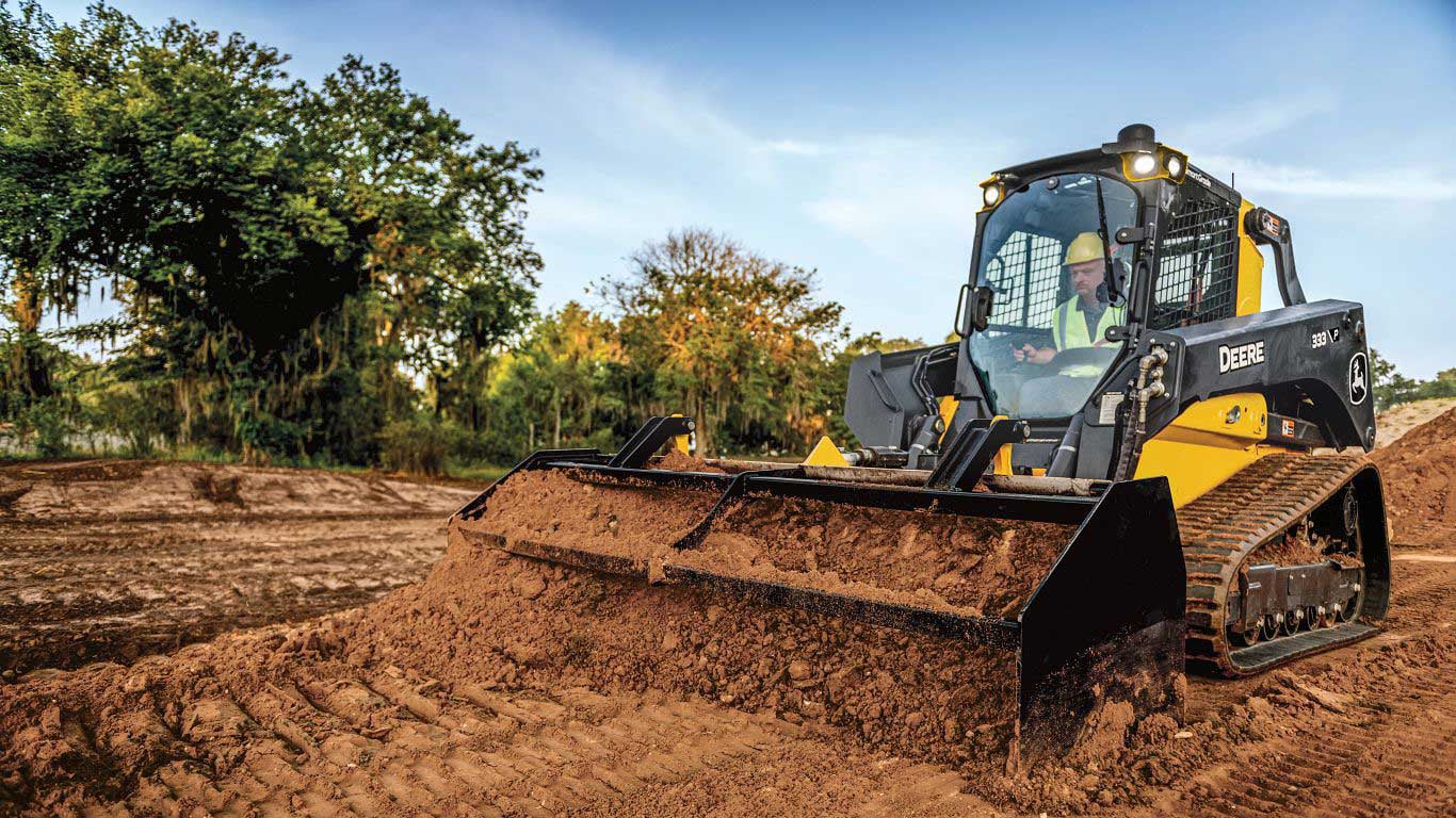 333 P-Tier Compact Track Loader with box blade attachment moves loose dirt on a jobsite