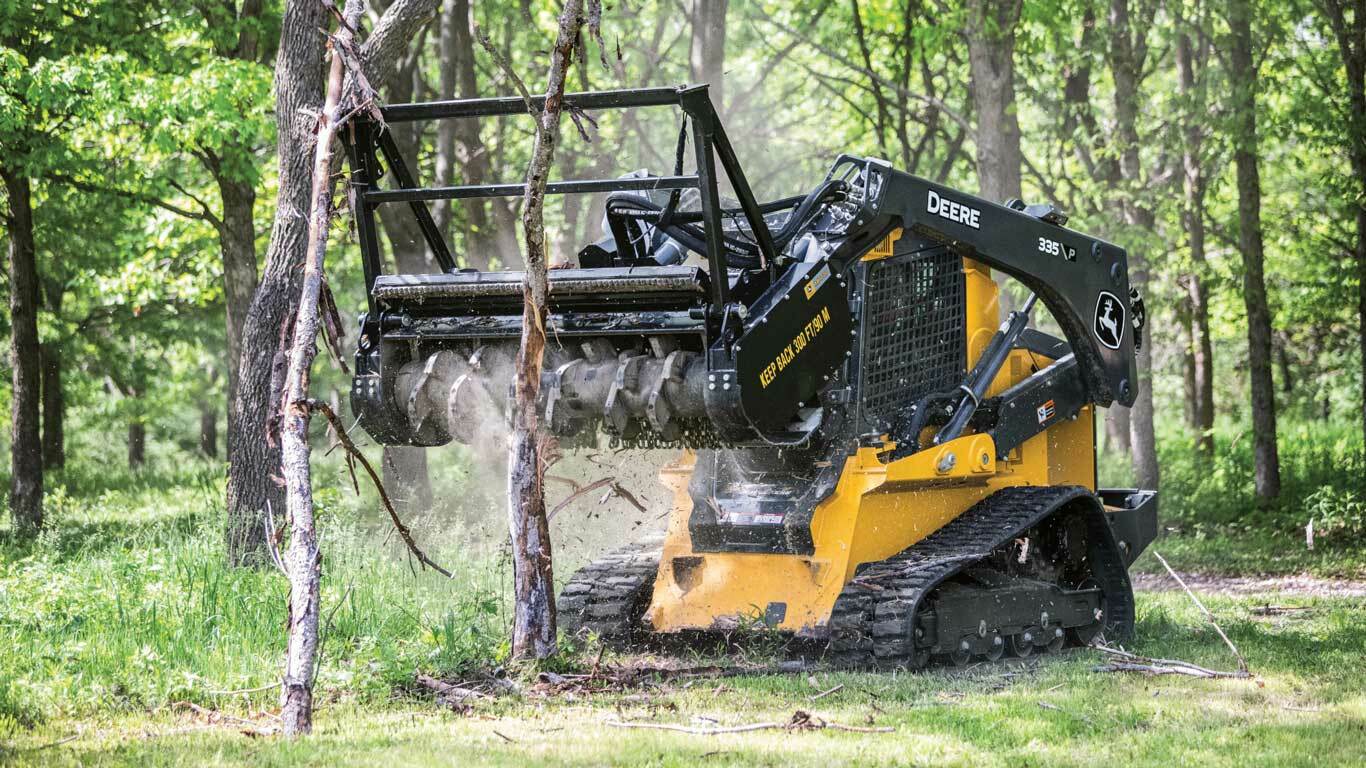 335 P-Tier Compact Track Loader with MH72D Mulching Head working in a wooded area