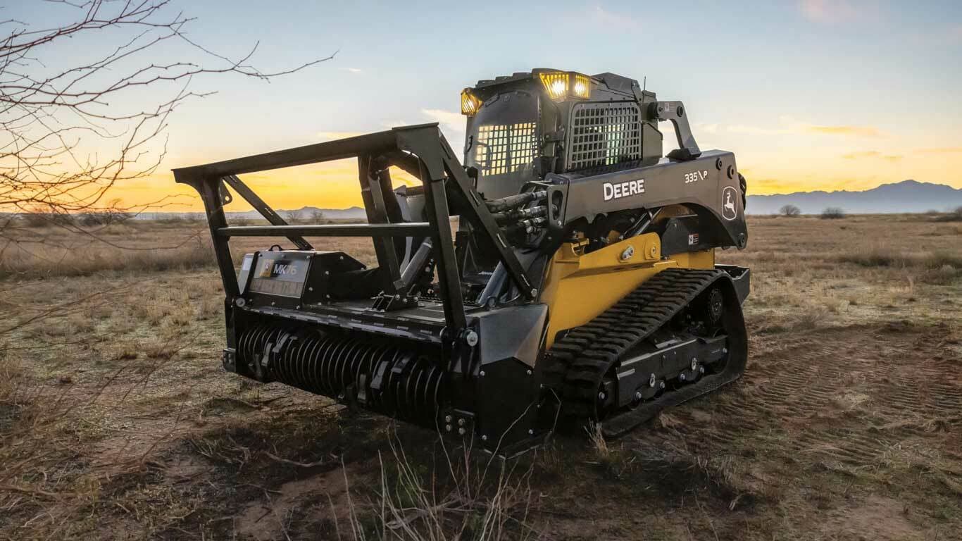 335 P-Tier Skid Steer with Tracks and MK76 Mulching Head attachment with mountains and sunset scene in the background