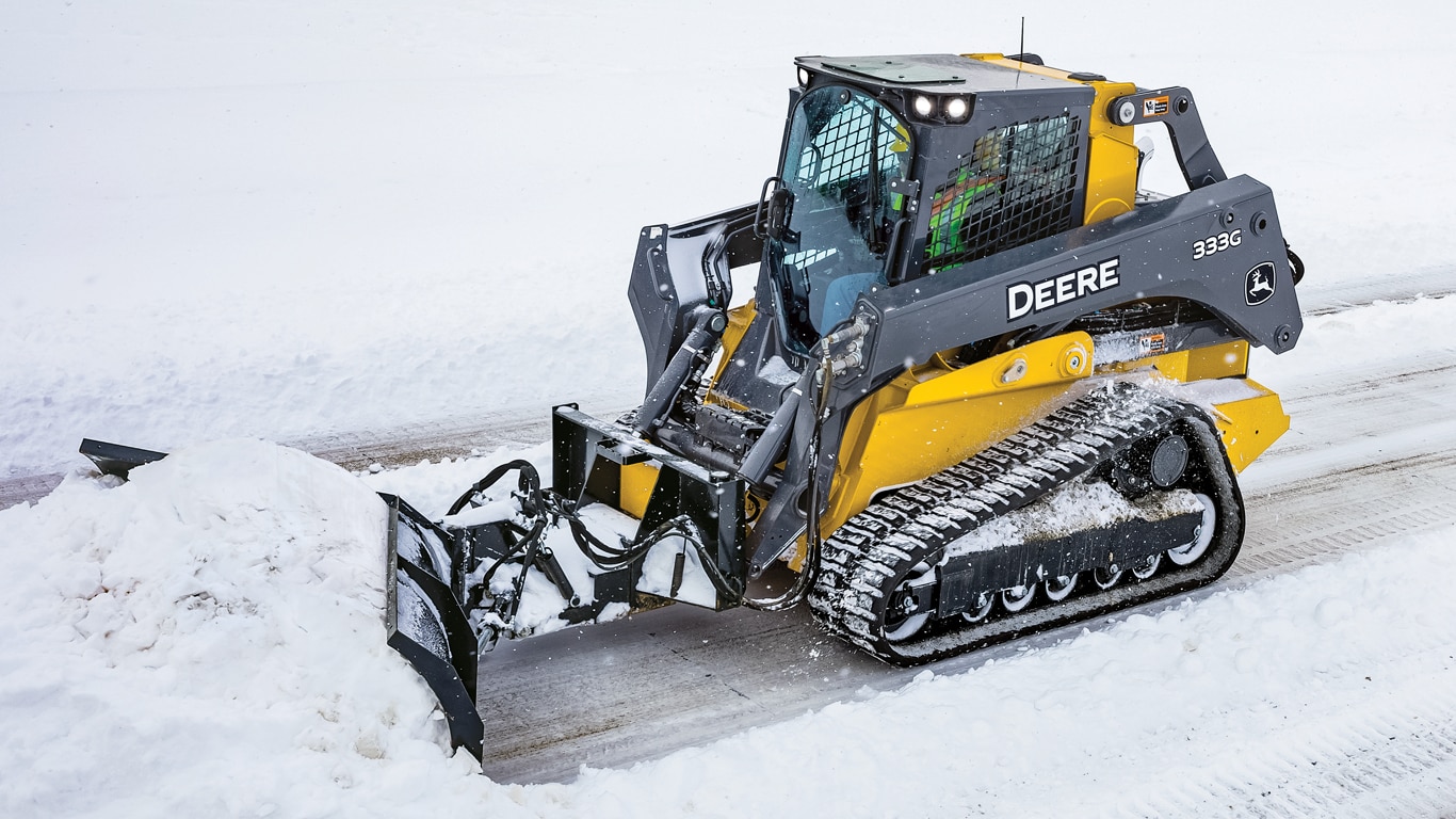 A 333G compact track loader with BV9 V Blade attachment plowing snow on a road.
