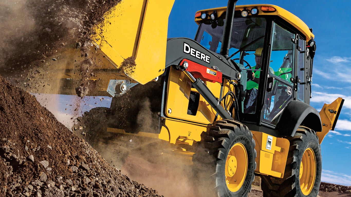 Close-up of an operator dumping dirt from a 310G Backhoe bucket.