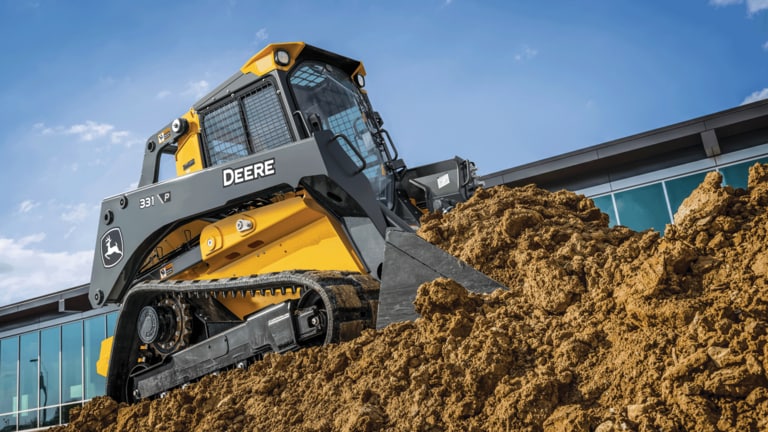331 P-Tier compact track loader driving onto hill of dirt and using bucket to move dirt.