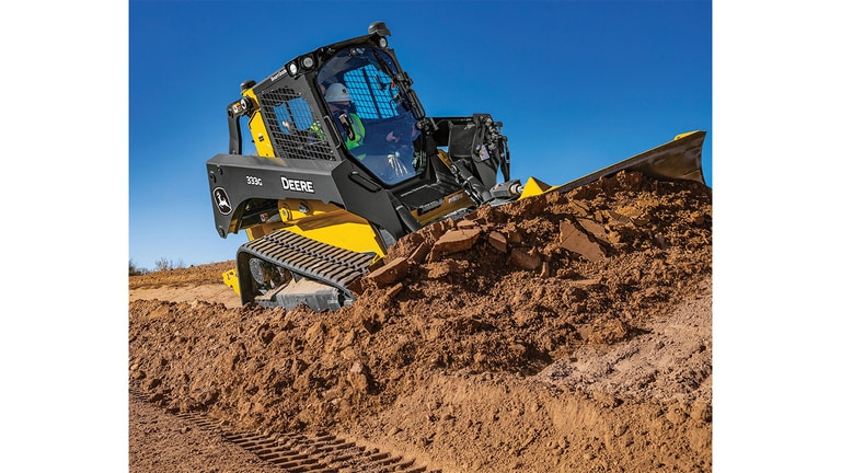 A 333G Compact Track Loader pushes dirt on angled terrain.