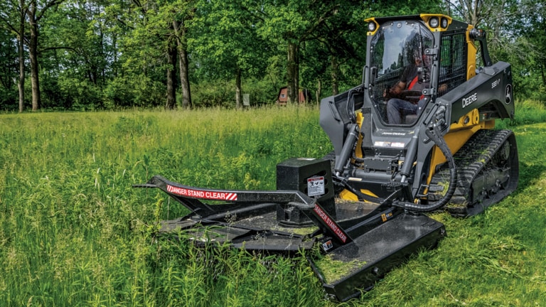 333 P-Tier compact track loader using rotary cutter to trim grass and brush.