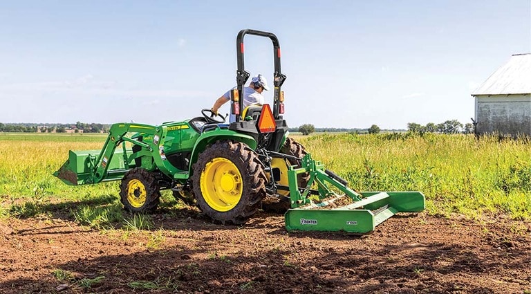 A person leveling out a field using a 3025E Tractor.