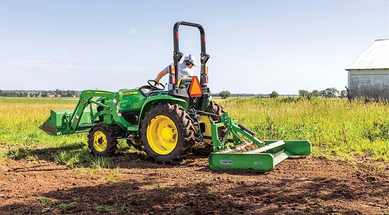 A person leveling out a field using a 3025E Tractor.