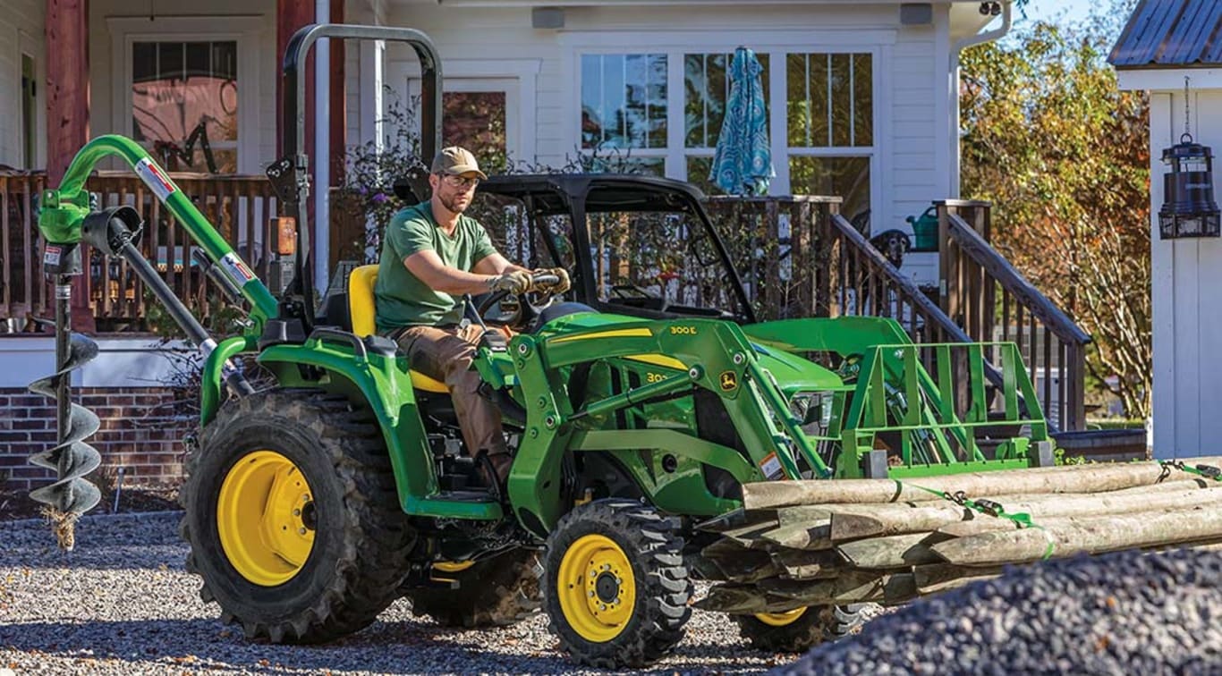 A person moving logs out of a gravel yard using his 3025E Tractor.