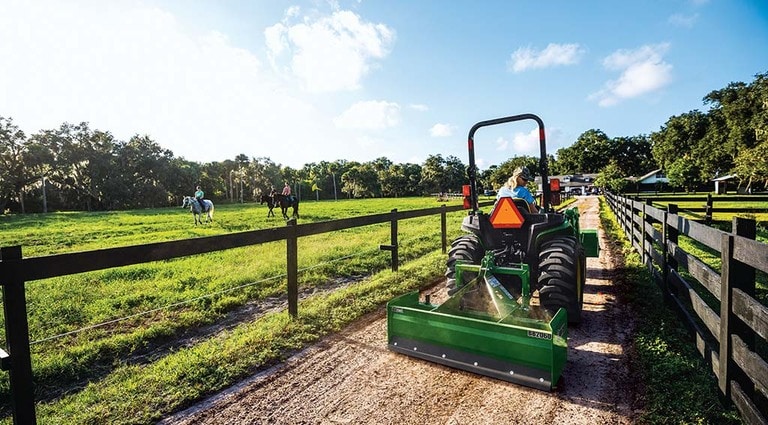 Person driving their 3025E Tractor along a dirt road.