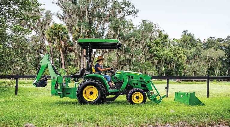 A person about to clip in an attachment to her 3025E Tractor.