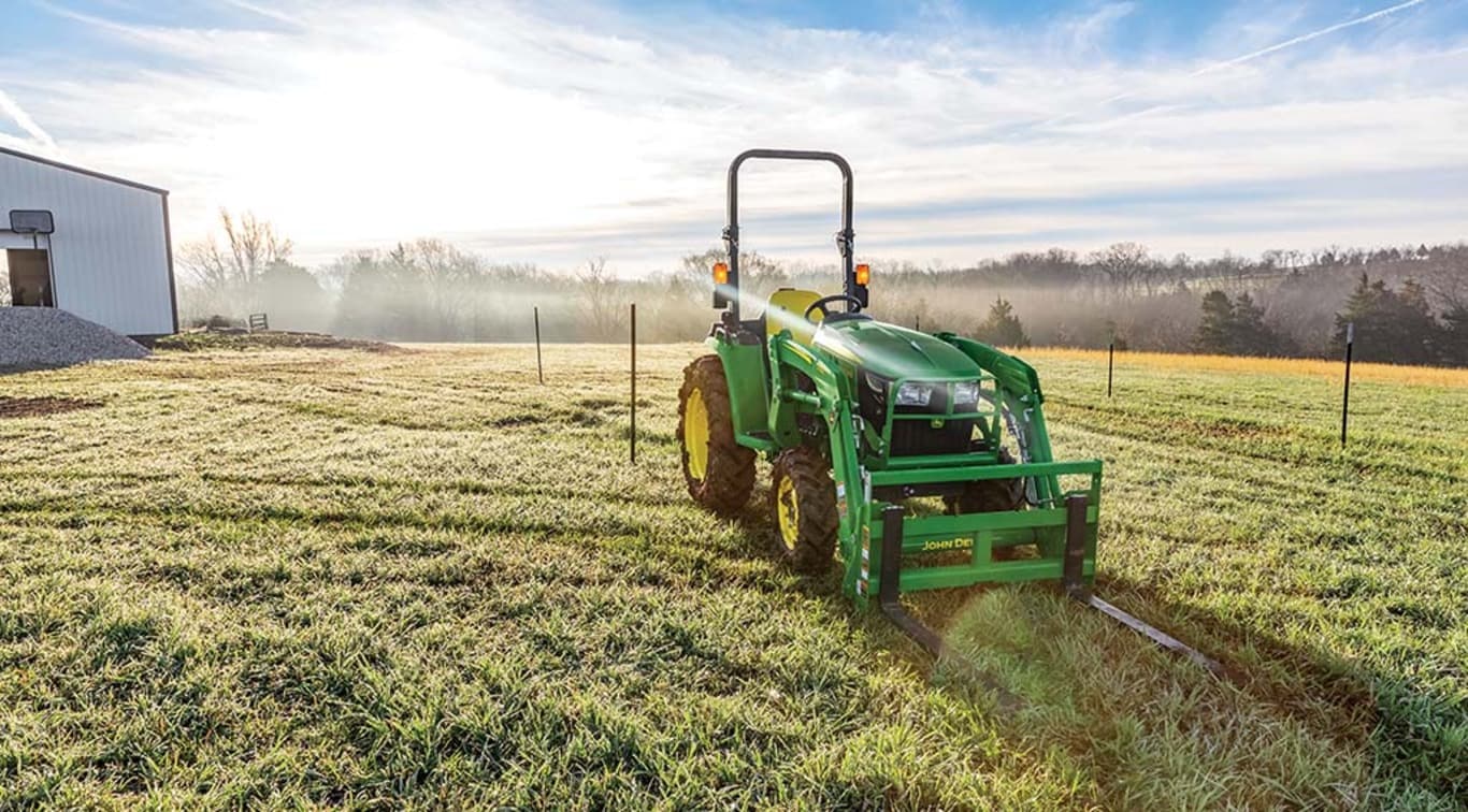 3038E John Deere Utility Tractor parked on farmland during a sunset