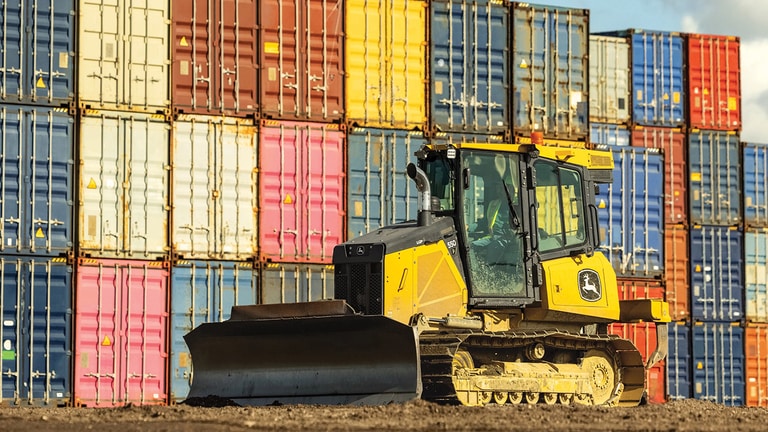 Bulldozer 550P frente a una pared de coloridos contenedores de transporte.