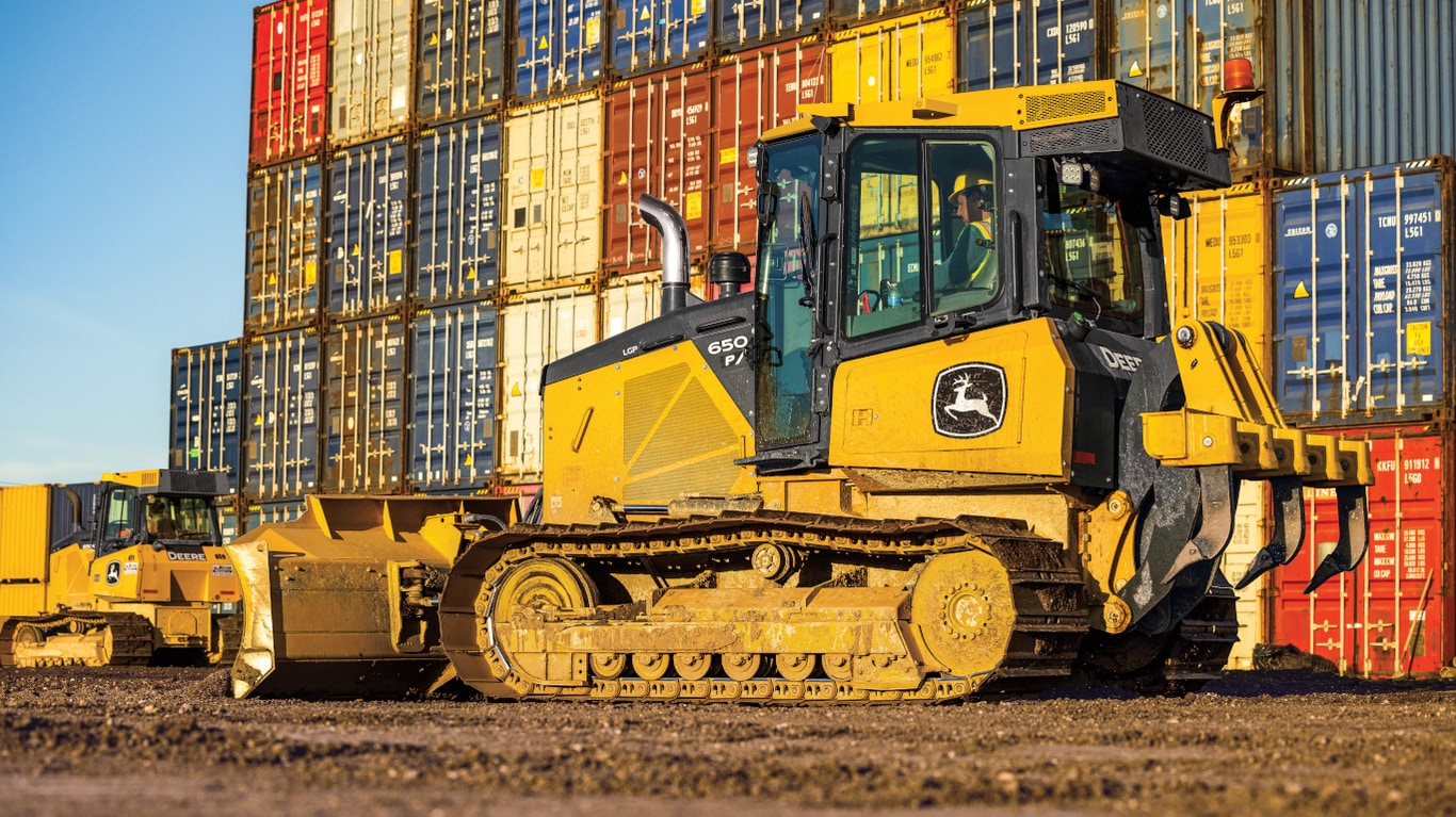 Left-side view of a 650P Dozer in front of a wall of colorful shipping containers.