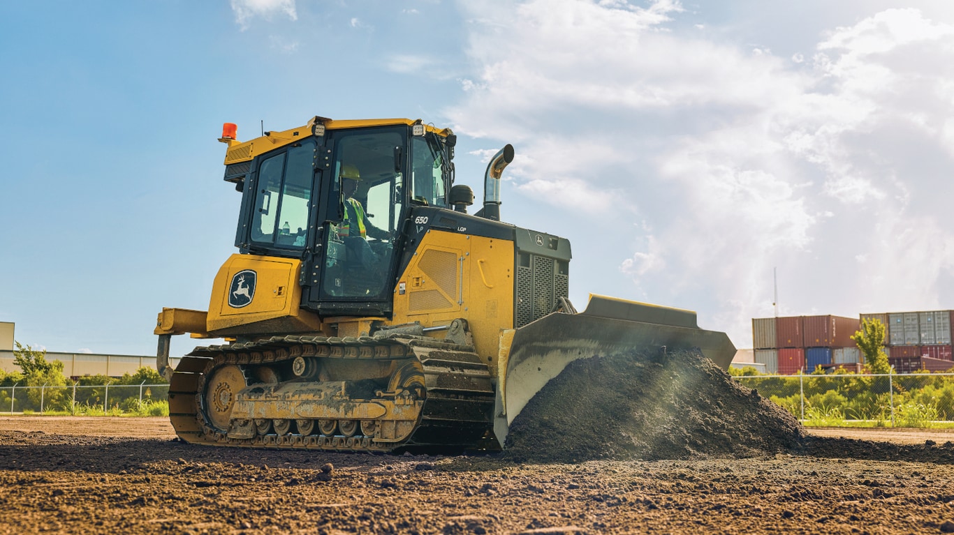  John Deere 650 P-Tier Bulldozer using a front shovel to scrape dirt off ground