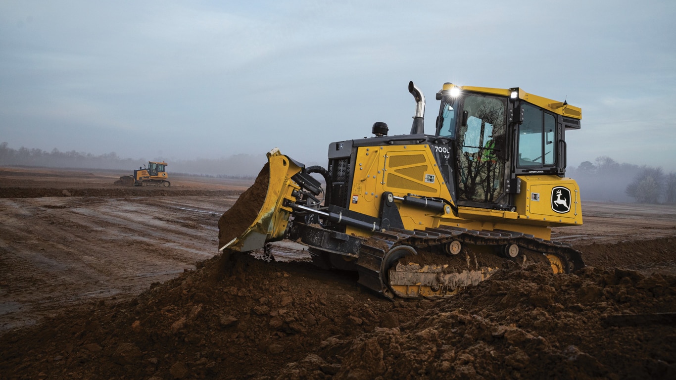 Deere 700L bulldozer pushes a pile of dirt