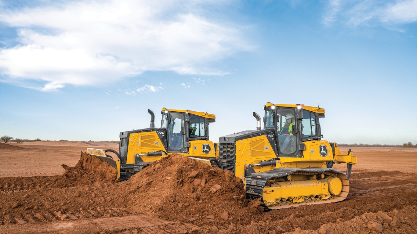 A 700L and 750L Dozer pushing dirt side by side on a worksite.