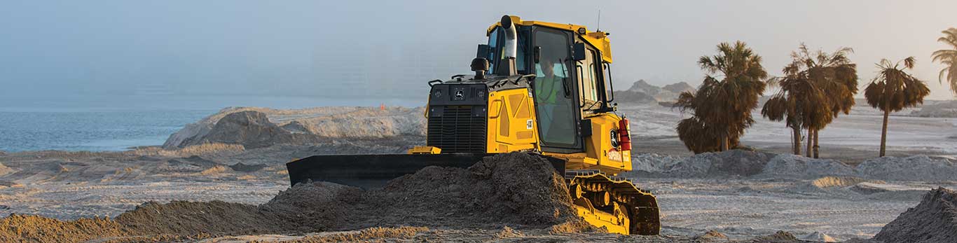 John Deere crawler dozer moving piles of organic material.