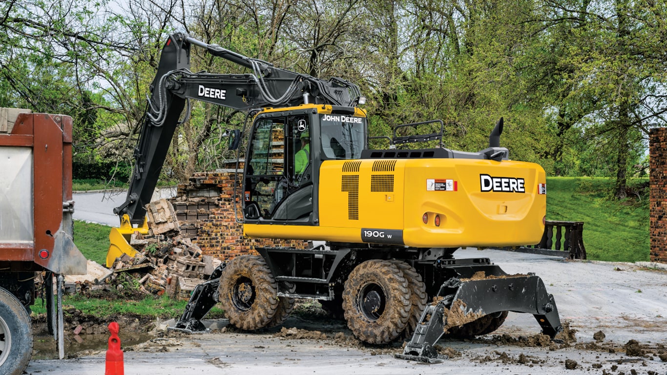 A 190GW Excavator scooping up brick from a demolished wall with an on-road truck to the left.