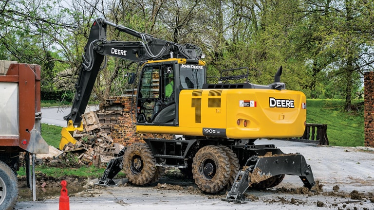 A 190GW Excavator scooping up brick from a demolished wall with an on-road truck to the left.