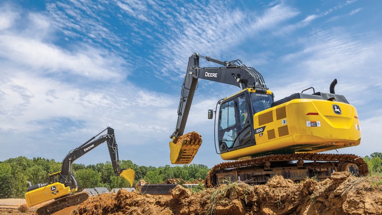 A 200G Excavator moving dirt at a worksite with a 180P-Tier Excavator also moving dirt in the background.