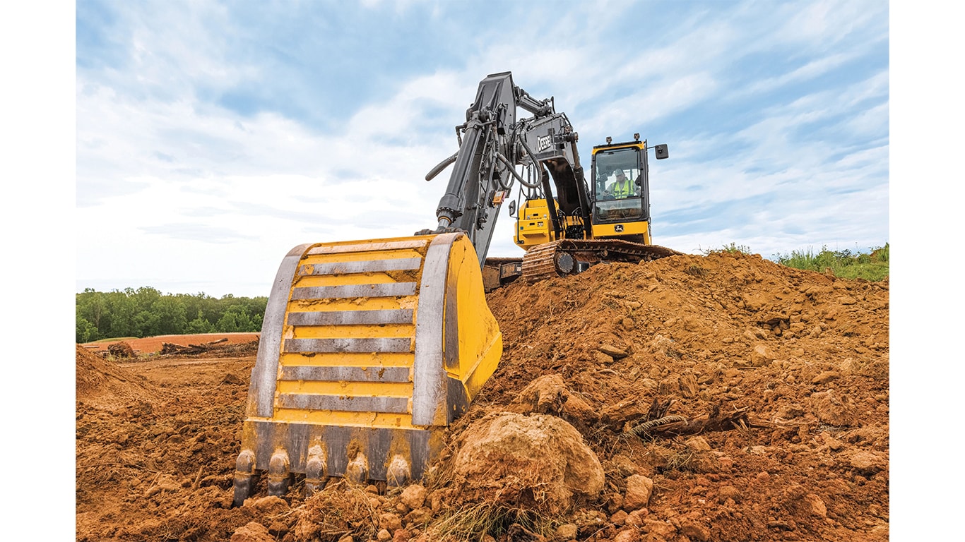 A close-up of the bucket on a 210P-Tier Excavator scooping dirt from a stockpile.