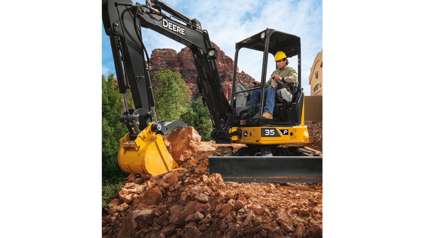 An operator using a 35P-Tier Excavator to move large pieces of rock with red-rock formations in the background.