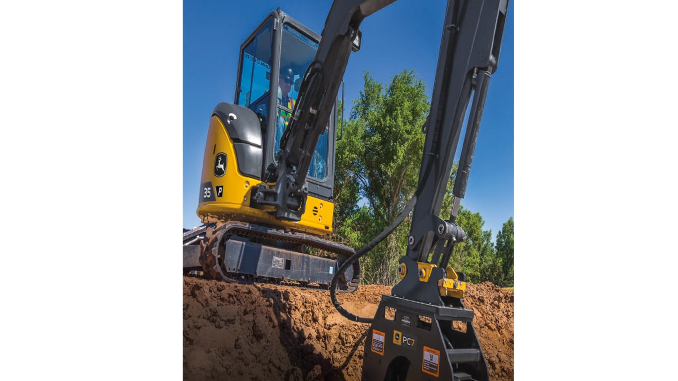 An operator using a 35P-Tier Excavator with P7 plate compactor attachment to compact dirt at a worksite.